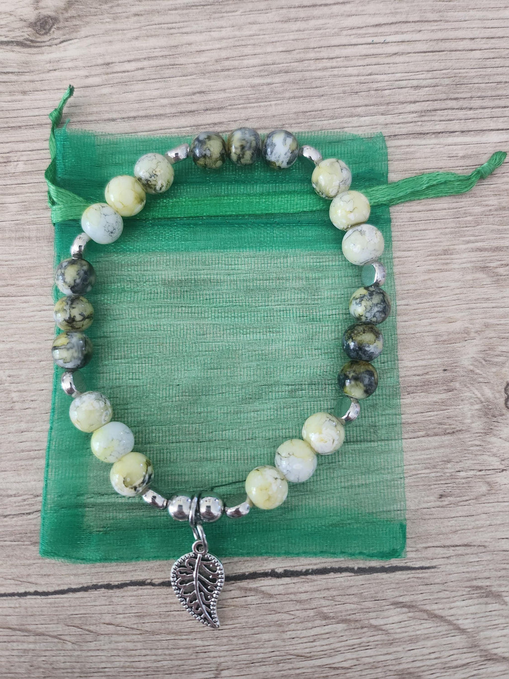 Bracelet en perles vertes, jaunes et grises, intercalaires argentés et breloque feuille