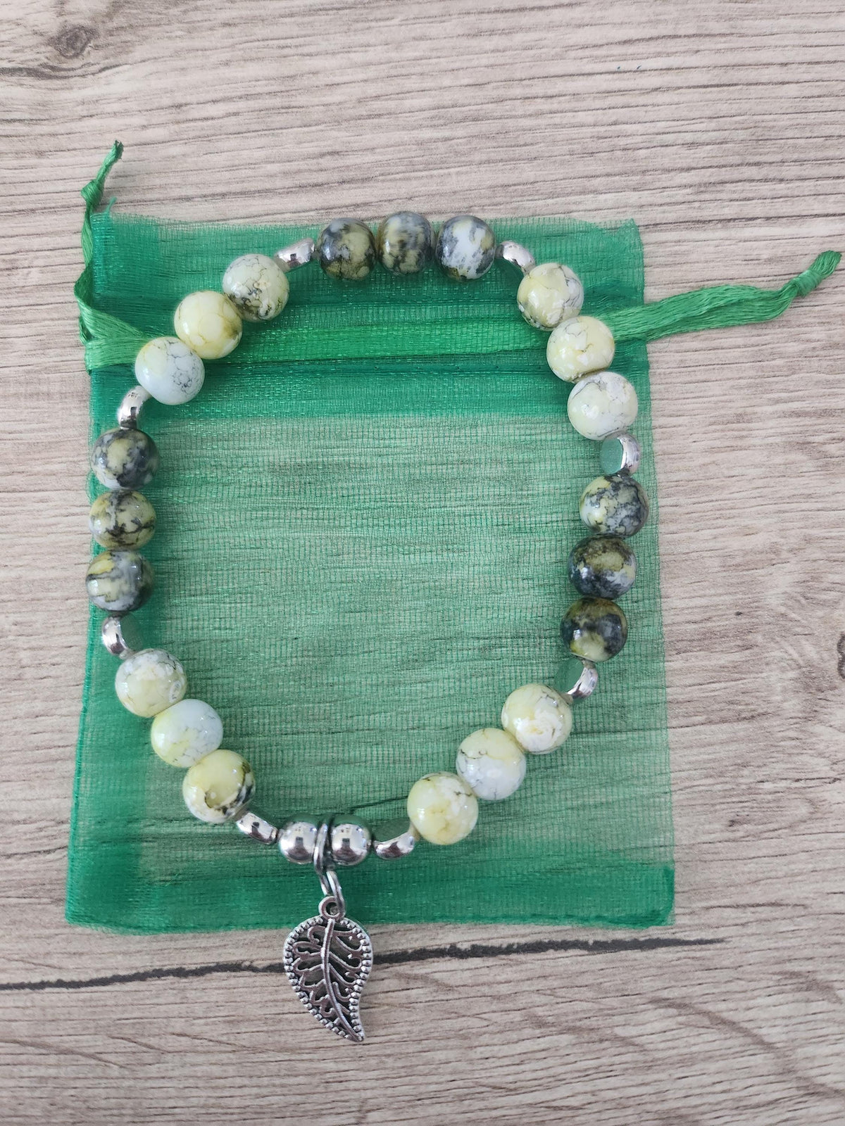Bracelet en perles vertes, jaunes et grises, intercalaires argentés et breloque feuille