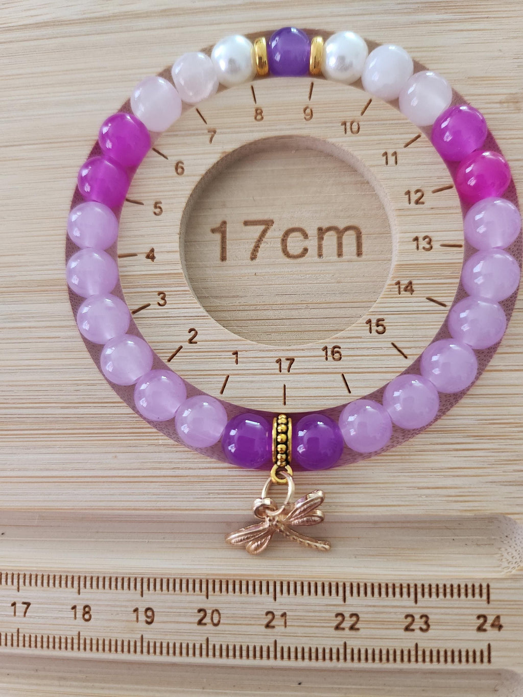 Bracelet en perles roses et violettes avec breloque libellule dorée -