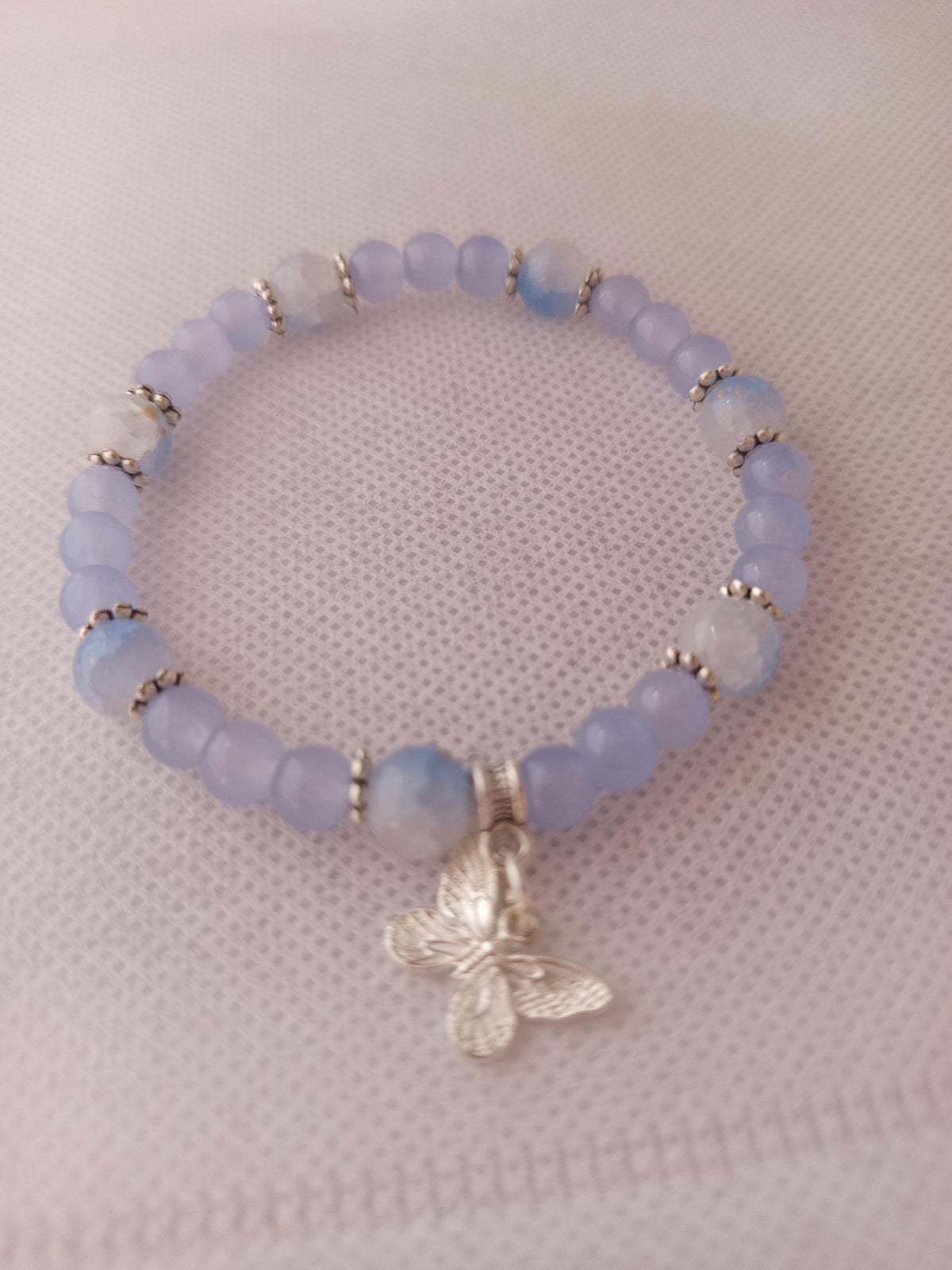 Bracelet en perles lavande, blanches et translucides avec breloque papillon -