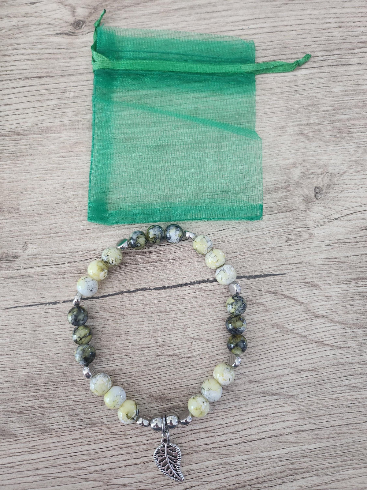 Bracelet en perles vertes, jaunes et grises, intercalaires argentés et breloque feuille