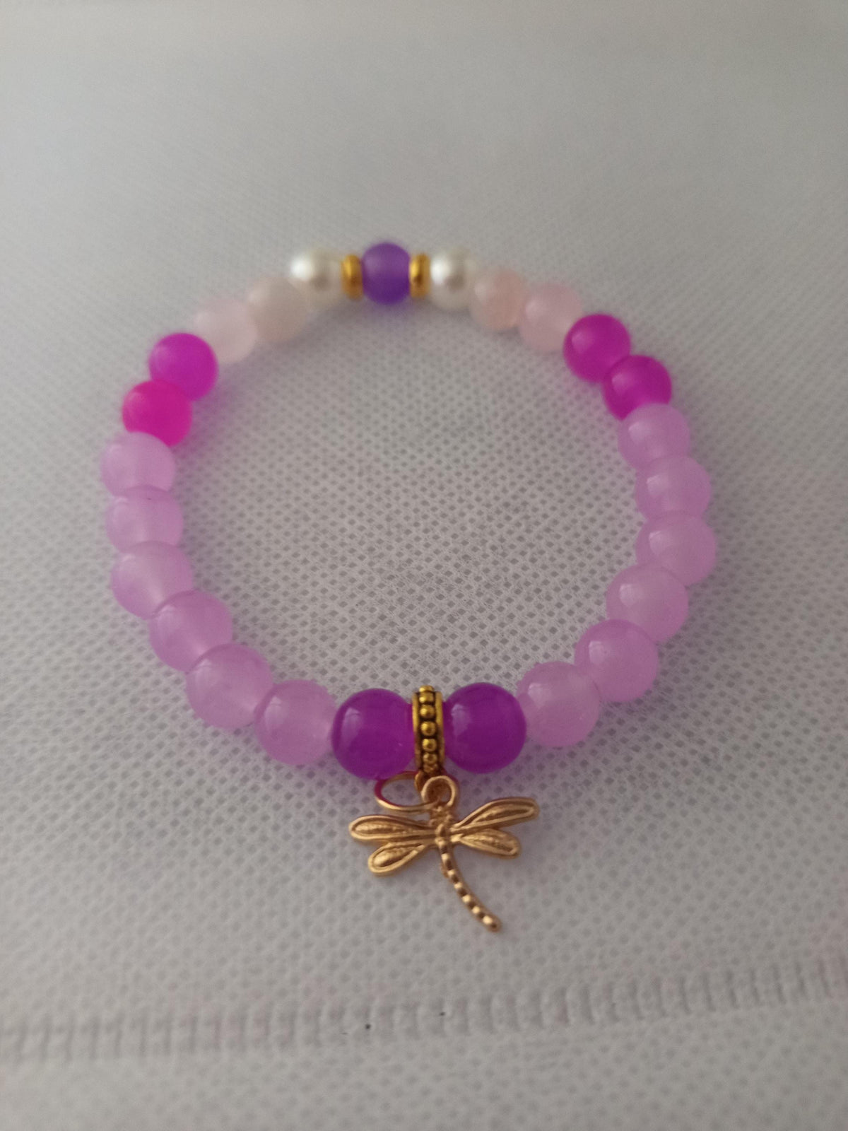 Bracelet en perles roses et violettes avec breloque libellule dorée -