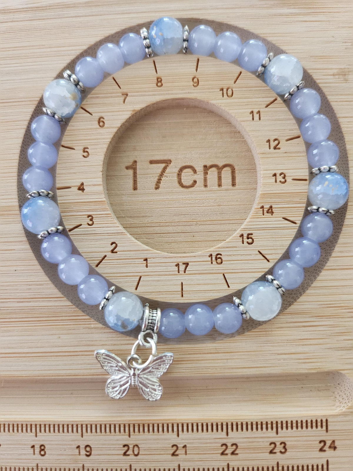 Bracelet en perles lavande, blanches et translucides avec breloque papillon -